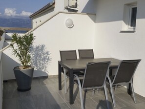 An outdoor patio with a table and chairs, a potted plant, and a view of the sea. - Lijepi pogled 2 / HR-10522-02 by Interhome (Vir)