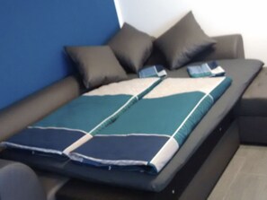 Ein Bett mit einer blau-weiß gestreiften Decke, einem dunkelbraunen Kopfteil und zwei Kissen.