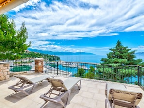 A terrace with lounge chairs overlooking a marina and a body of water. - PALACE PAULINA 1A / HR-10316-01 by Interhome (Novi Vinodolski)