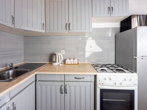 A kitchen with grey cabinets, a stainless steel sink, a gas stove, and a built-in oven. - Apartmani Zoricic 1 / HR-11028-01 by Interhome (Novi Vinodolski)