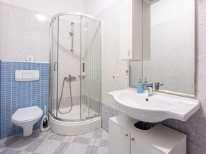 Ein modernes Badezimmer mit Duschkabine aus Glas, einem weißen Waschbecken und einer Toilette.