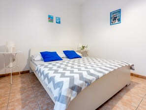 A bedroom with a bed, a bedside table, a lamp, and two wall art pieces. - Apartmani Zoricic 1 / HR-11028-01 by Interhome (Novi Vinodolski)