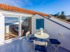 A balcony with a patterned floor, a table with chairs, and a view of the sea. - Apartmani Zoricic 3 / HR-11028-03 by Interhome (Novi Vinodolski)
