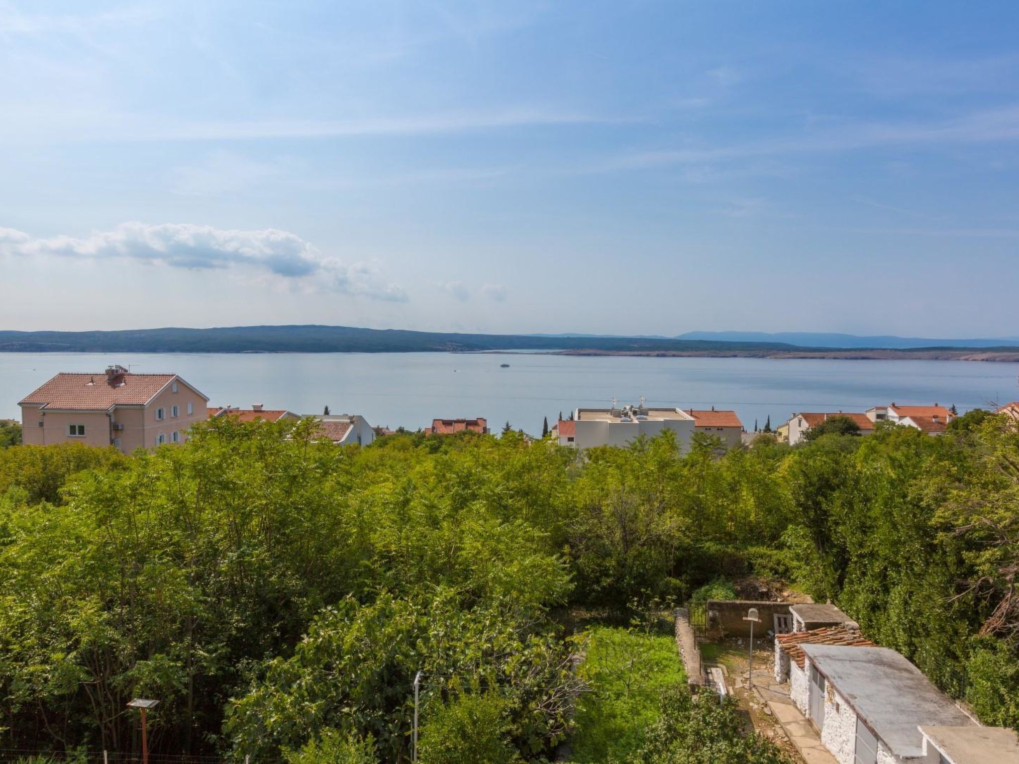 A coastal residential area with houses, a clear sky, and a body of water in the distance.