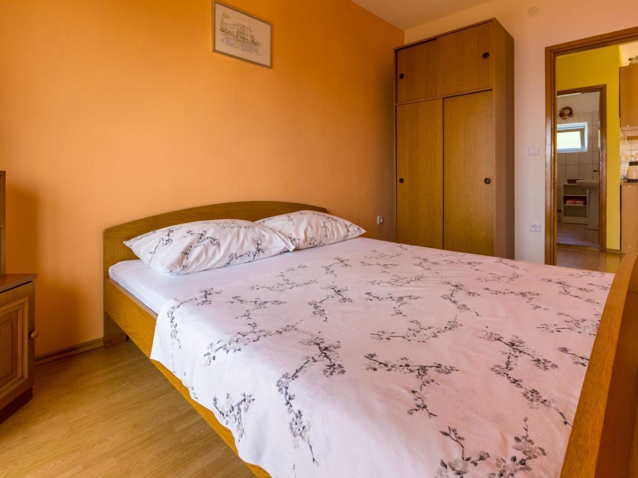 Une chambre à coucher avec un lit, une armoire en bois et un tableau encadré accroché au mur.