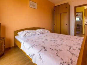 Ein Schlafzimmer mit einem Bett, einem Holzschrank und einem gerahmten Bild an der Wand.