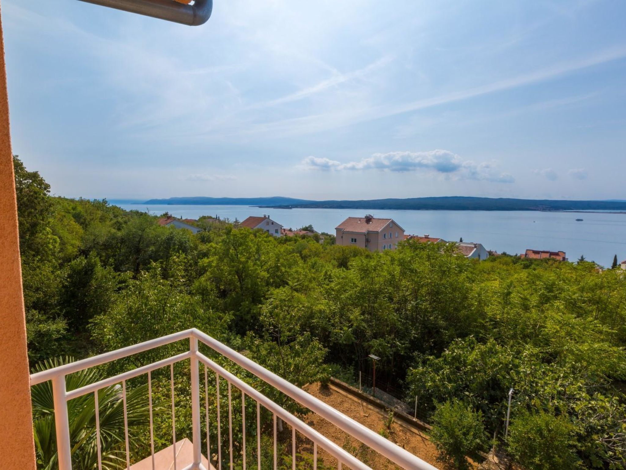 A balcony with a view of a lake and distant mountains.