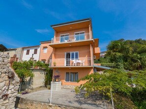 A two-story building with balconies, a stone wall, and surrounding greenery. - TORBICA 2 / HR-09082-02 by Interhome (Crikvenica/Dramalj)