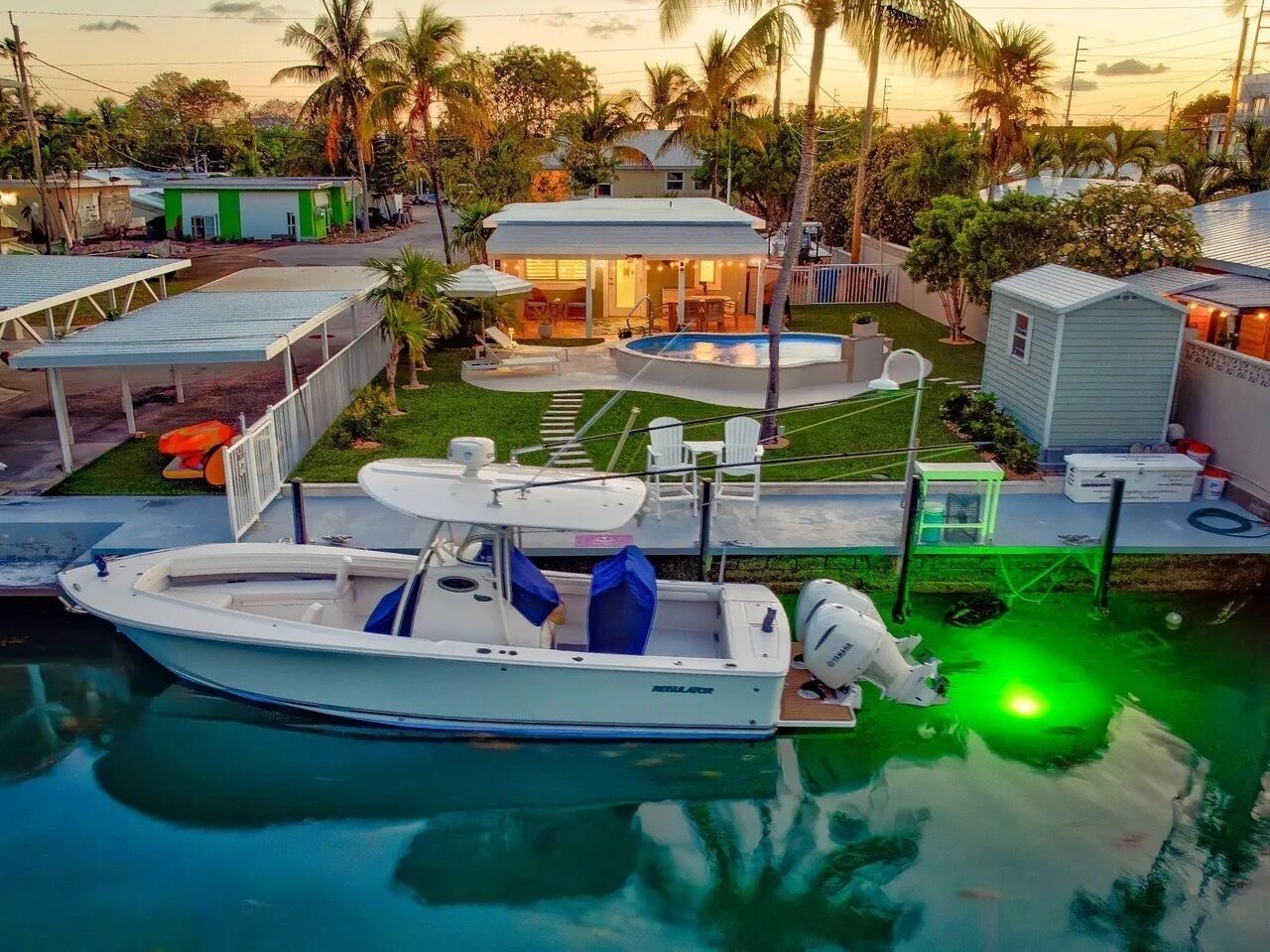 A boat docked at a marina with a pool, a covered area, and a small building in the background.