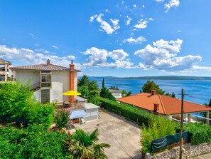 Ein Küstenanwesen mit Terrasse und Blick auf das Meer, bewölkter Himmel.
