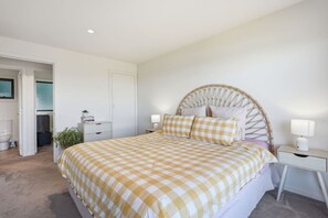 A bedroom with a checkered bedspread, a round headboard, bedside lamps, and a small bedside table.