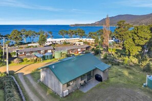 A coastal property with a large building, a swimming pool, and a view of the sea. - Coastal 2BR Escape, Steps to Beach, Dining and Bar (Eaglehawk Neck)