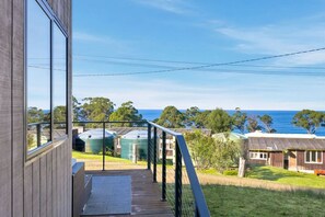 A balcony with a view of the sea and surrounding houses.