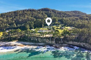 A coastal property with a beachfront, dense forested hill, and a house icon indicating a location.
