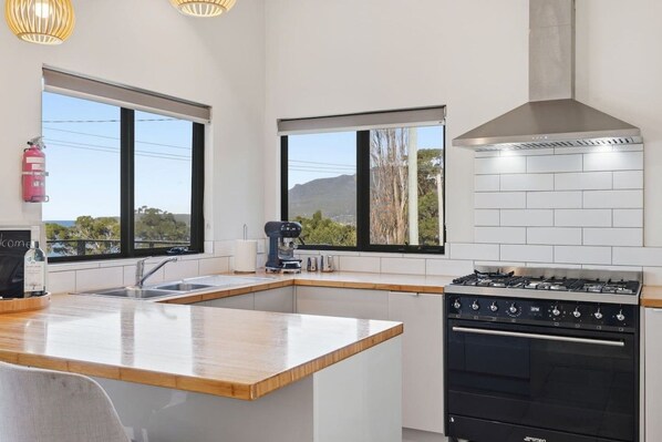 A modern kitchen with a central island, a stove, and a coffee machine.