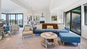 Uma sala de estar moderna com um sofá, poltronas, uma mesa de centro e vista para o exterior.