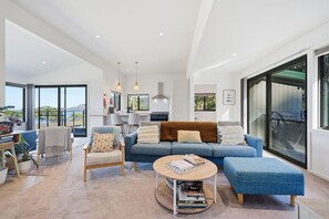 A modern living room with a sofa, armchairs, a coffee table, and a view of the outdoors. - Coastal 2BR Escape, Steps to Beach, Dining and Bar (Eaglehawk Neck)