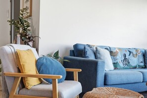 A living room with a grey armchair, a blue sofa, and a woven basket.