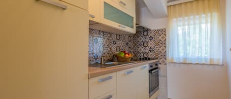 A kitchen with light-colored cabinets, a microwave, a stove, and a tiled backsplash.