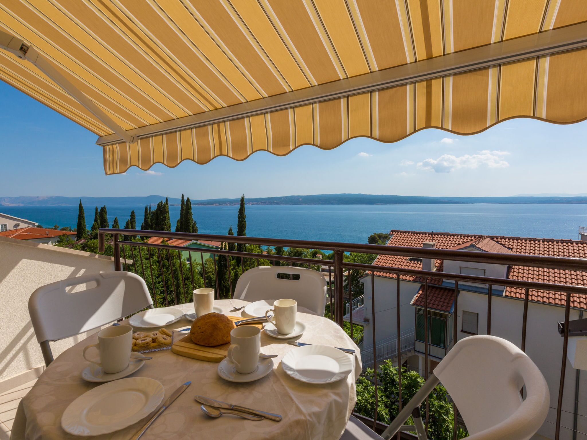 Une terrasse avec une table dressée pour deux personnes, offrant une vue sur la mer.