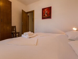 Ein Hotelzimmer mit einem Bett, einem Gemälde, einer Tür und einem Nachttisch.