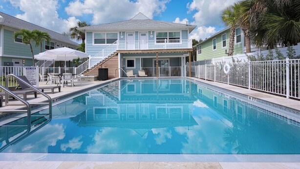 A swimming pool with a clear blue sky and clouds above. - The Kove  (Fort Myers Beach)