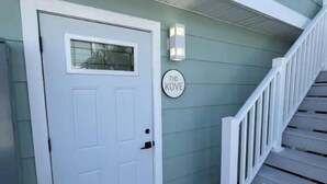 A white door with a window, a white mailbox, and a staircase with white railings. - The Kove  (Fort Myers Beach)