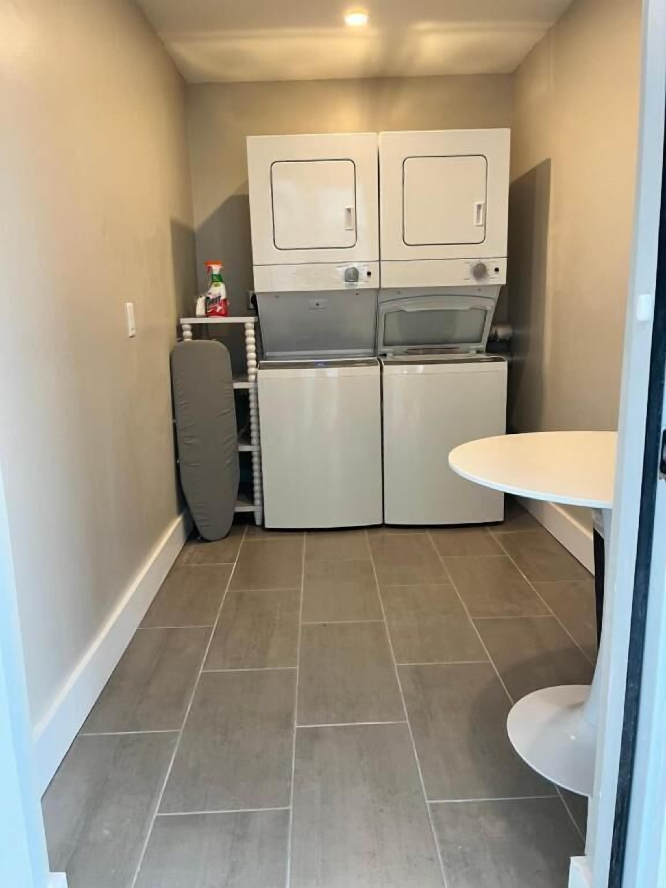 A compact kitchen with two white cabinets, a small refrigerator, and a white table.