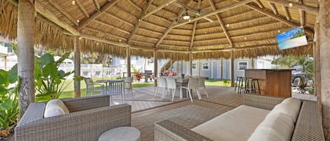 An outdoor seating area with wicker furniture and a thatched roof.