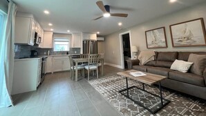 A modern living room with a sofa, coffee table, and a dining area with chairs. - The Kove  (Fort Myers Beach)