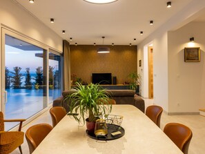 A modern living room with a large dining table, comfortable seating, a TV, and a view of the outdoors. - Villa Murn / HR-11124-01 by Interhome (Crikvenica)