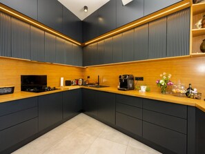 A modern kitchen with dark cabinetry, a wooden countertop, and a coffee machine. - Villa Murn / HR-11124-01 by Interhome (Crikvenica)