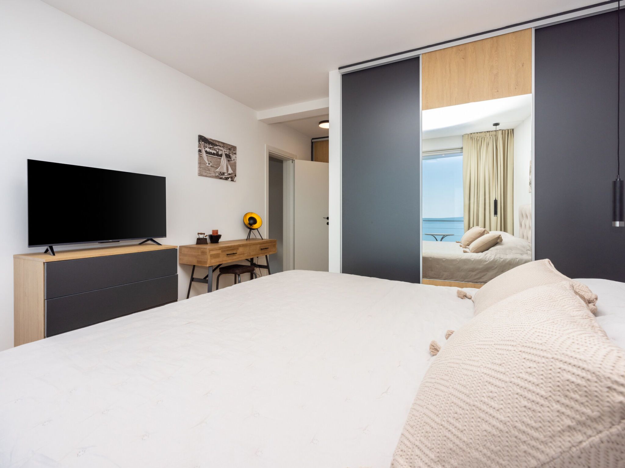 Une chambre d’hôtel avec un lit, un bureau, une télévision et une vue sur la mer.