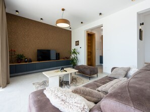 A modern living room with a flat-screen TV, a coffee table, a sofa, and a large plant. - Villa Murn / HR-11124-01 by Interhome (Crikvenica)