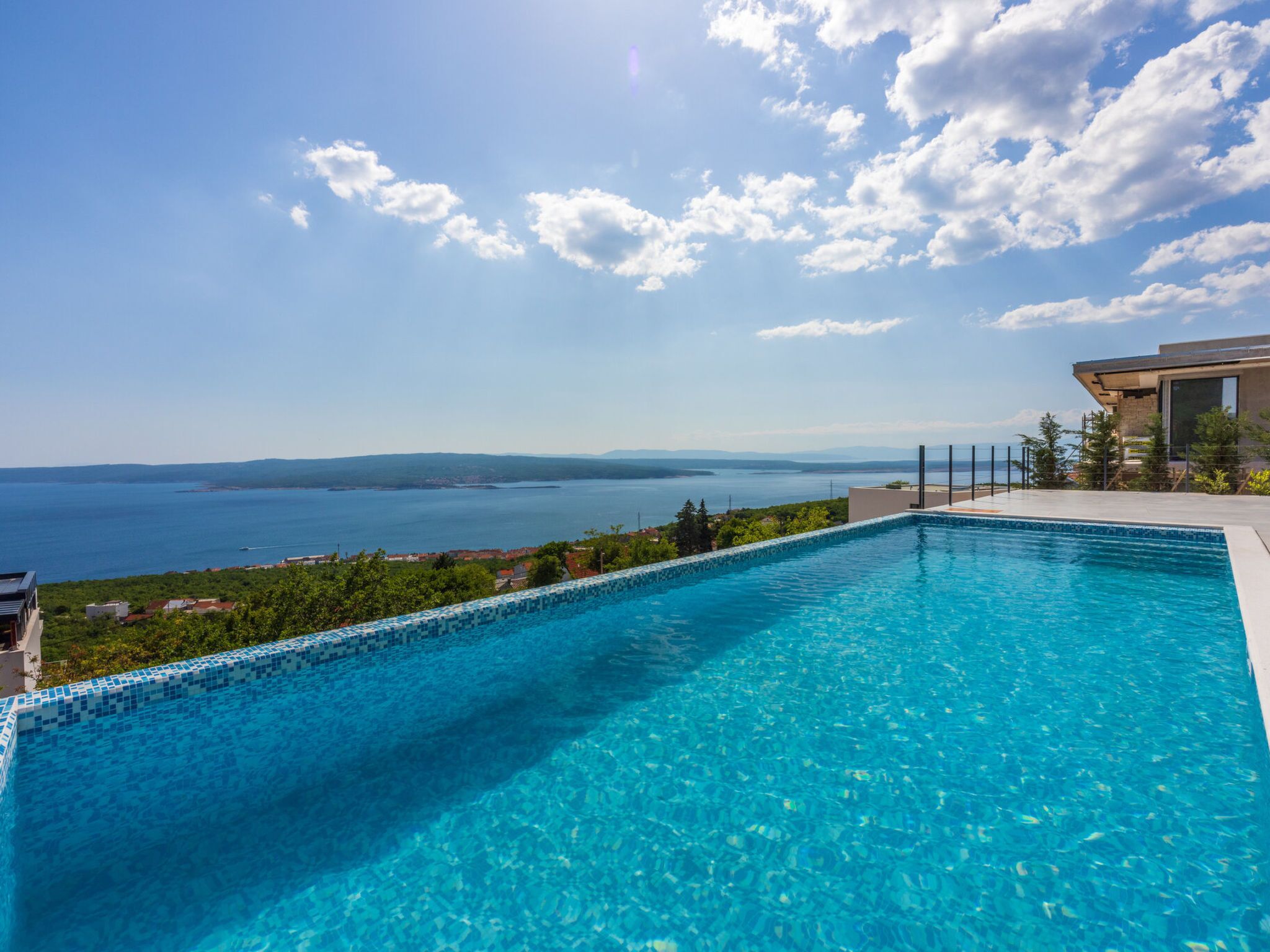 A swimming pool with a view of the sea and distant mountains.