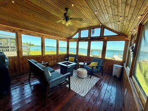 Una terraza de madera con ventilador de techo, una mesa y sillas, y vista al agua.