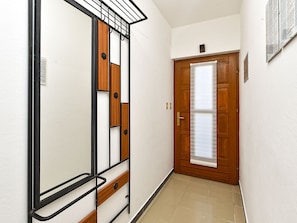 A hallway with a wooden door, a metal-framed mirror, and a tiled floor. - Apartment 2372 by Interhome (Drenje)