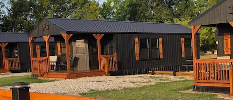Eine Reihe von Holzhütten mit Holzdeckterrassen und Metalldächern, umgeben von Kies und Gras.