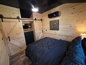 Ein Schlafzimmer mit einem Bett, einem Schminktisch, einem Fernseher und einem Deckenventilator.