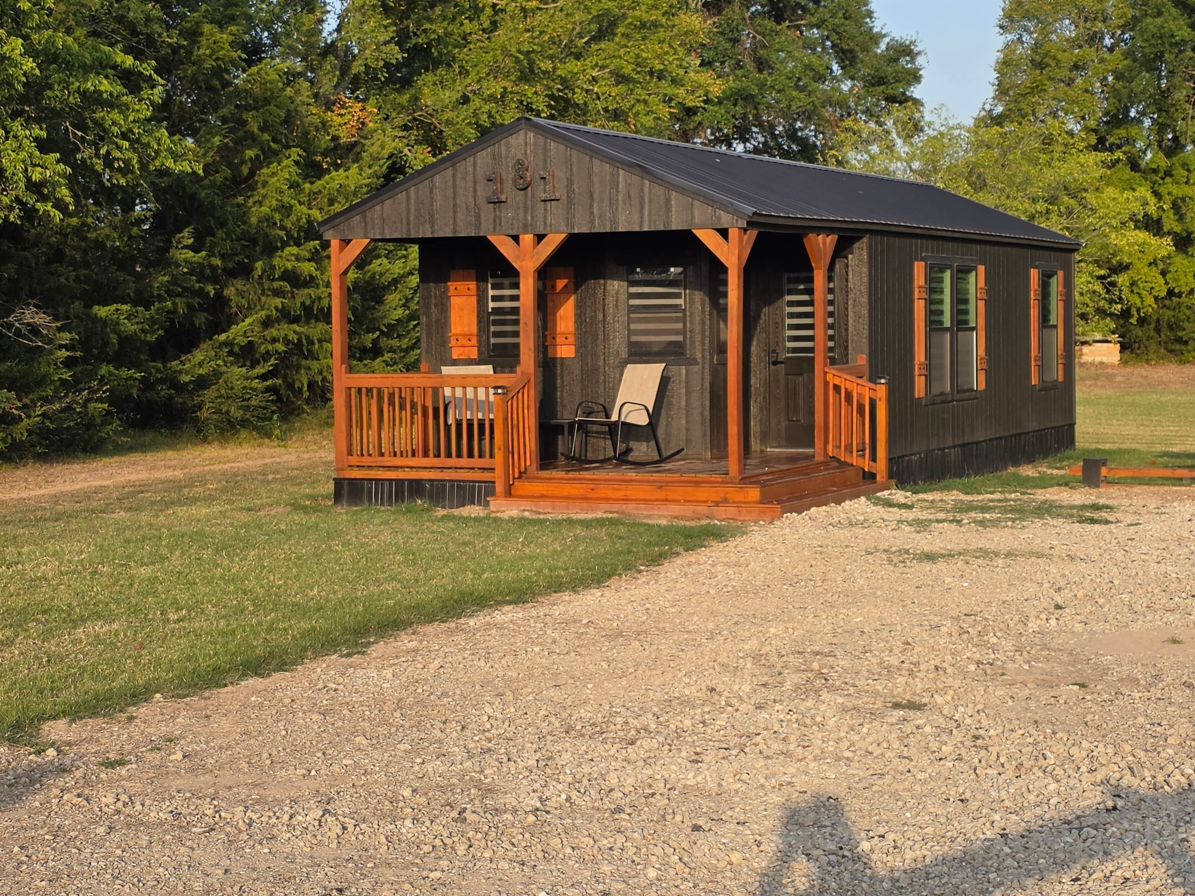 A small cabin with a porch, a rocking chair, and a bench.