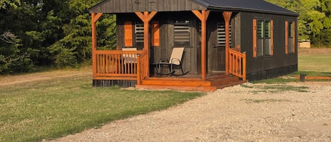 A small cabin with a porch, a rocking chair, and a bench.