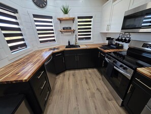 Una cucina moderna con mobili neri, piani di lavoro in legno, forno integrato e angolo caffè.