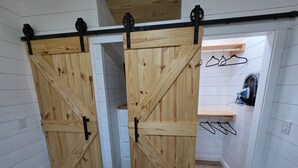 Een kamer met een houten schuifdeur, een klein plankje en een kledingroede.