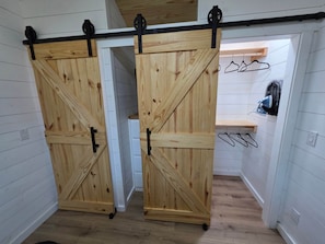 Ein Zimmer mit einer Holztür, einem kleinen Regal und einer Kleiderstange.