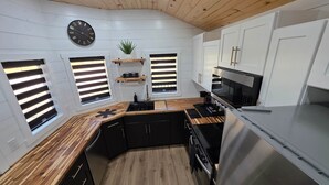 Een moderne keuken met een houten plafond, witte wanden en inbouwapparatuur.