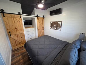 A bedroom with a bed, a wardrobe with a mirror, and a wall-mounted air conditioning unit. - Hay Meadow 189 Texas USA (Van Zandt County)
