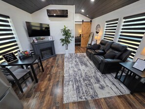 A modern living room with a fireplace, leather sofa, and a flat-screen TV mounted on the wall. - Hay Meadow 189 Texas USA (Van Zandt County)