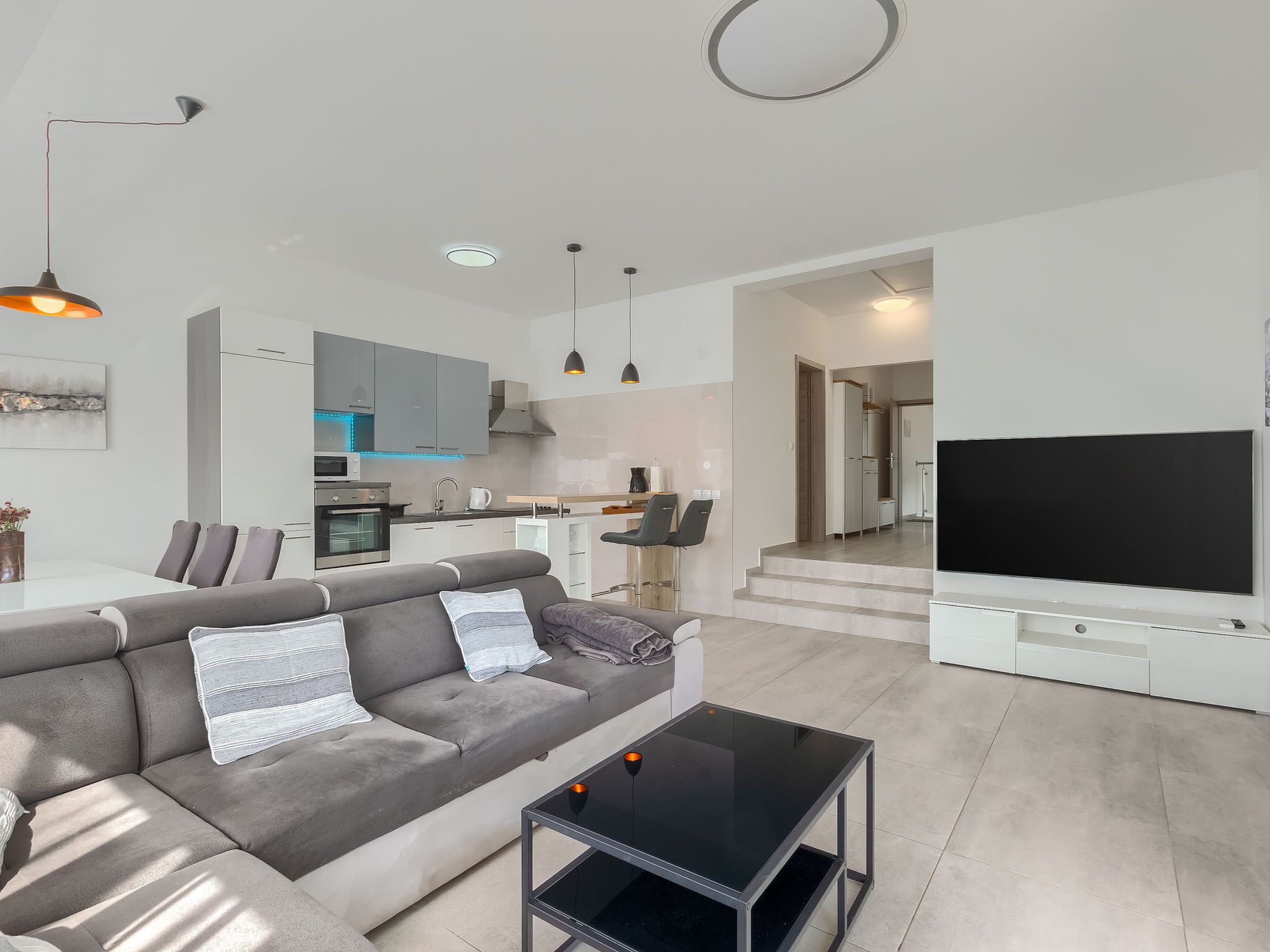 A modern living room with a grey sofa, a coffee table, and a flat-screen TV.