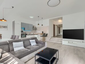 Ein modernes Wohnzimmer mit grauem Sofa, Couchtisch und Flachbildfernseher.