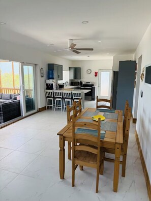 A modern kitchen with a dining area, including a table with chairs and a ceiling fan.